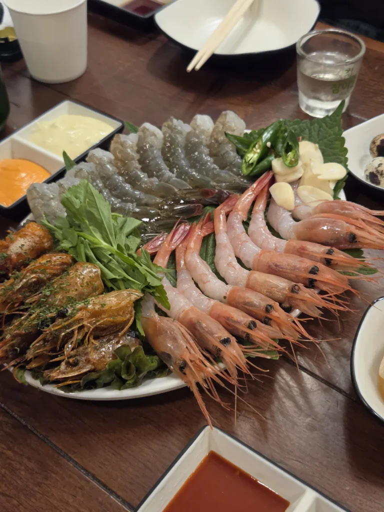 Raw shrimp and shrimp heads arranged with leafy greens, garlic and sliced green chillies.